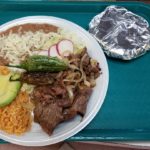 A plate containing rice, refried beans, and steak, showcasing a delicious Mexican meal