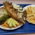 A plate featuring grilled fish served with refried beans, rice, and a side of French fries